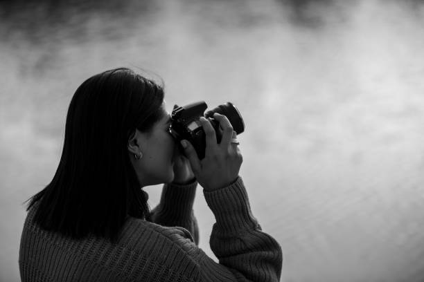 Woman taking sunset pictures at the lake while camping alone.
