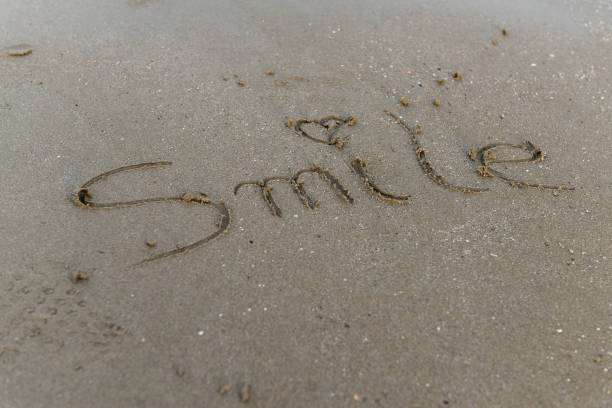 istock Smile message handwritten on the beach sand. 1396300451