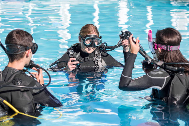 Scuba dive training in the pool with a smiling instructor Scuba dive training in the pool with a smiling instructor teaching two students scuba diving stock pictures, royalty-free photos & images