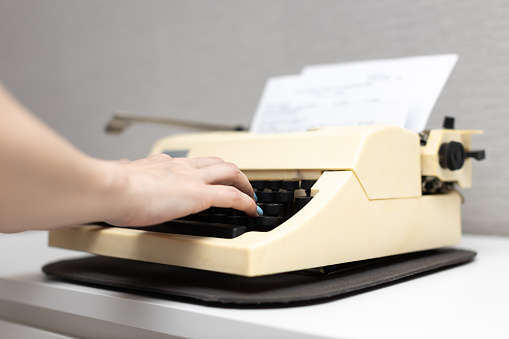 woman typing text on an old typewriter