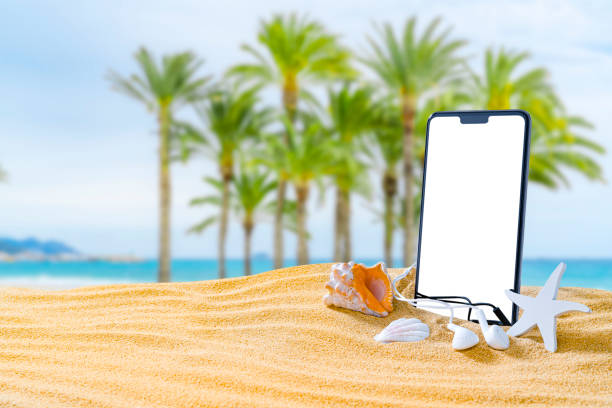 istock Phone and earbuds standing on tropical beach sand. Copy space 1396304896