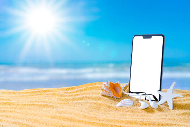 istock Phone and earbuds standing on golden beach sand. Copy space 1396304897