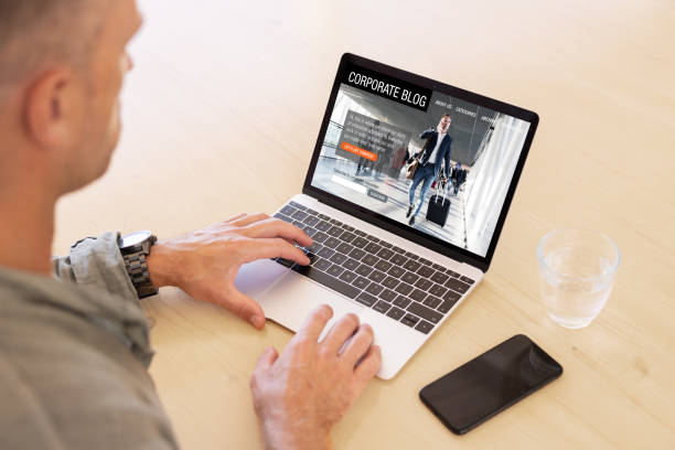 istock Man using laptop computer with sample corporate blog website on the screen. 1396307697