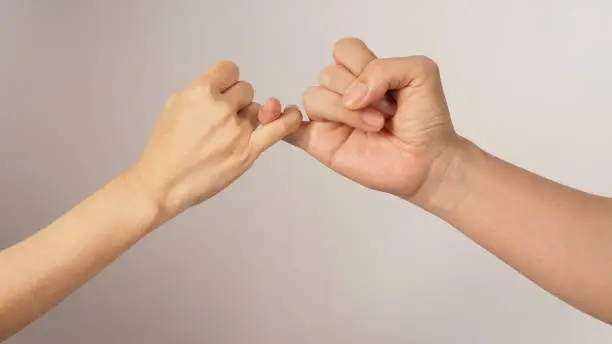 Man and woman do Pinky promise or pinky swear hands sign on white background.