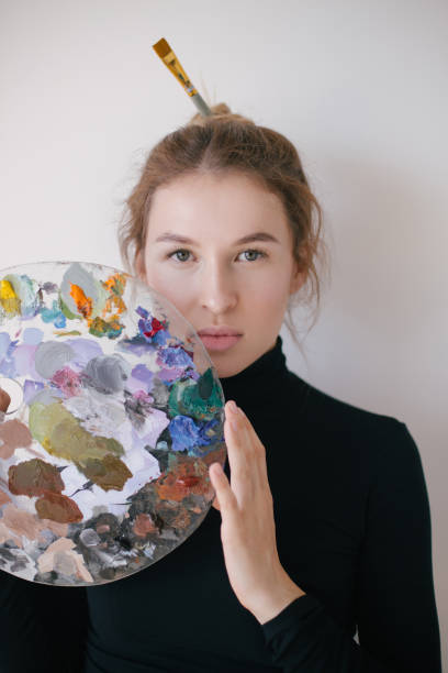 istock Woman artist posing with her painting tools in art studio. 1396309719