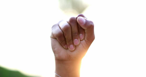 Black hand raised fist in air in political protest, close-up clench fist stock photo