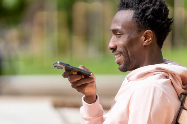 istock Man sending an audio message with smartphone in the park 1396315435