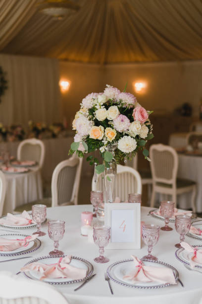 istock Table setting at the wedding reception. Floral compositions with beautiful flowers and greenery, candles, laying and plates on a decorated table. 1396316599