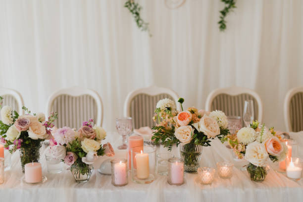 istock Table setting at the wedding reception. Floral compositions with beautiful flowers and greenery, candles, laying and plates on a decorated table. 1396316612