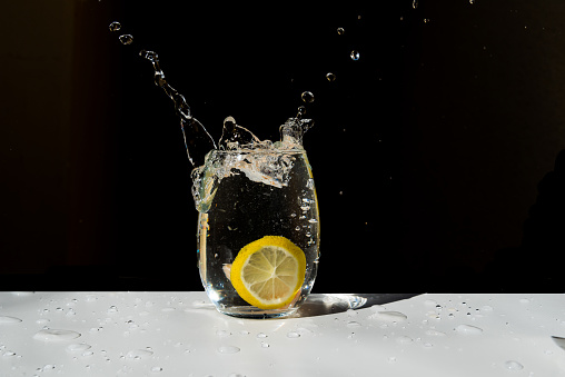 Close-up of lemon with water drops against green background.