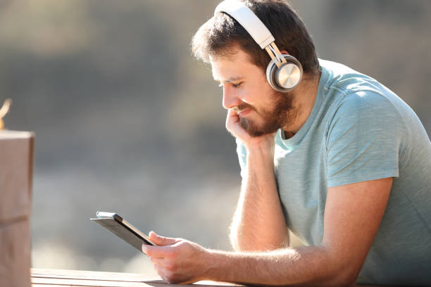 istock Man watching videos on tablet with headphones 1396316883