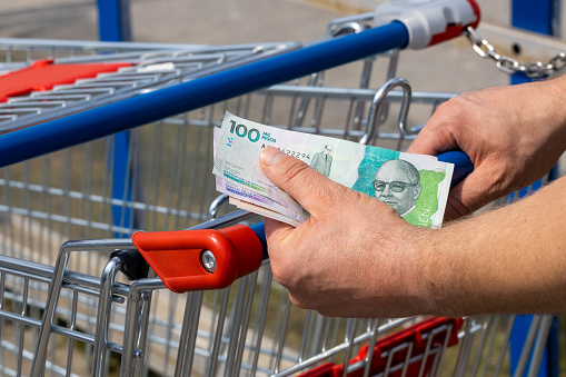 Shopping cart in a supermarket and Colombia pesos, held in hand, Concept of inflation, Rising costs of living, Home budget