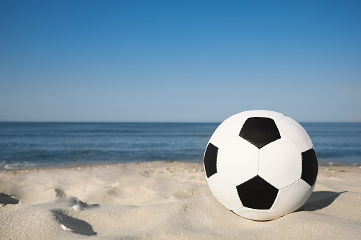 Soccer ball on beach, space for text. Football equipment