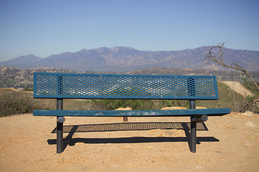 Single metal bench overlooking mountain range on hiking trail