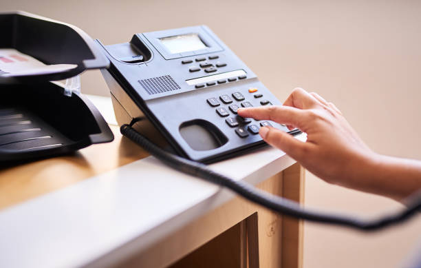 Closeup of a woman making a call on a telephone in an office alone. One female only dialling a phone number with her fingers on a keypad at a receptionist's front desk. Administrator and secretary consulting and transferring calls from a help desk Closeup of a woman making a call on a telephone in an office alone. One female only dialling a phone number with her fingers on a keypad at a receptionist's front desk. Administrator and secretary consulting and transferring calls from a help desk dialling phone stock pictures, royalty-free photos & images