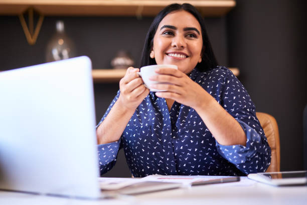 istock Confident indian businesswoman drinking coffee while working alone in an office. One female only taking a break and looking thoughtful while enjoying a warm cup of tea at her desk 1396322714