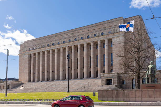 Finnish flag flying in front of Finnish parliament building in Helsinki Helsinki, Finland - May 8th 2022: Finnish flags flying in front of Finnish parliament building in Helsinki, on international Mother's day. finnish culture stock pictures, royalty-free photos & images