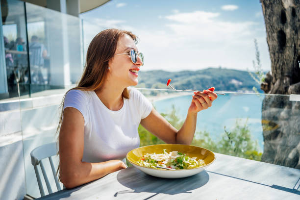 美しい景色を望むランチを楽しむ女性 - vacations restaurant sunlight outdoors ストックフォトと画像
