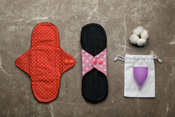istock Reusable cloth pads, menstrual cup and cotton flower on brown table, flat lay 1396326385