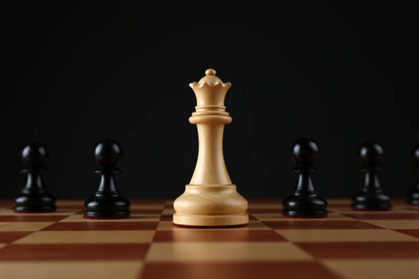 reine blanche parmi les pions noirs sur échiquier en bois sur fond sombre - chess leisure games chess queen skill photos et images de collection