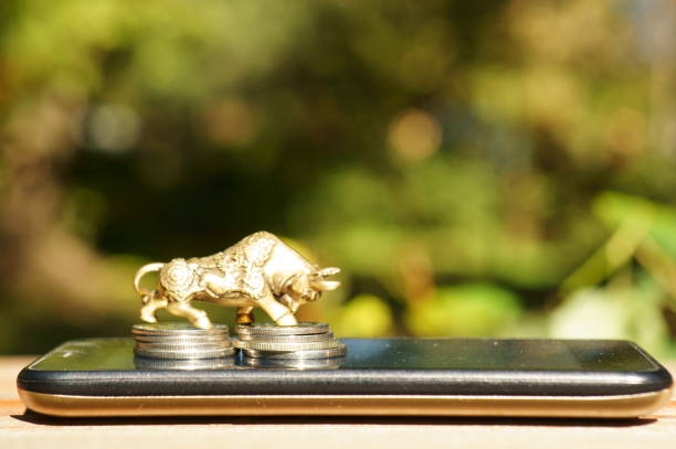istock Bull figurine with coins on a mobile phone. 1396327361