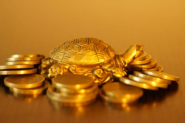 istock Metal turtle with coins on a gold background. 1396327742