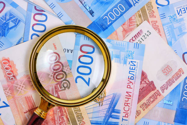 istock Magnifying magnifier against background Russian rubles denominations five and two thousand. 1396328791