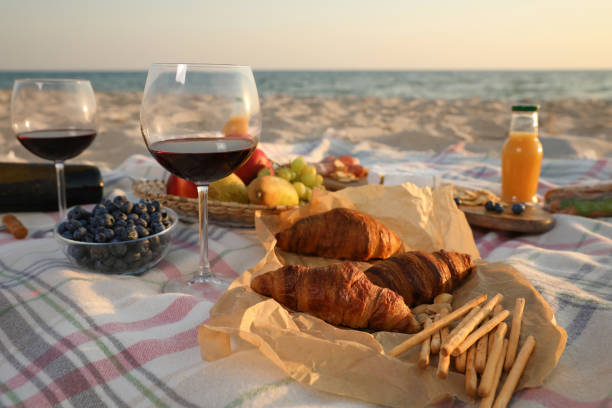 istock Blanket with wine, juice and snacks for picnic on sandy beach 1396329002