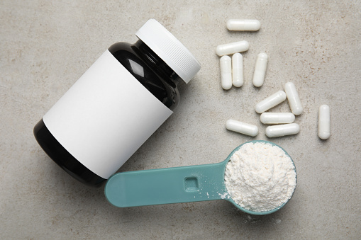 Amino acid pills and powder on grey table, flat lay