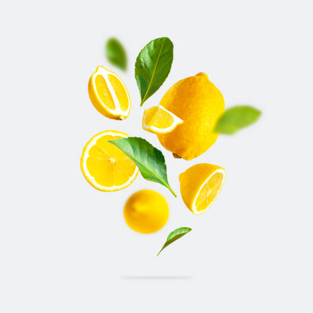 juicy ripe flying yellow lemons, green leaves on light gray background. creative food concept. tropical organic fruit, citrus, vitamin c. lemon slices. summer minimalistic bright fruit background - tropisch-motief-fotos stockfoto's en -beelden