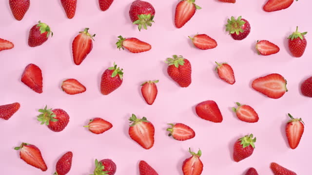 Creative healthy food pattern with sweet organic strawberries on pastel pink background. Stop motion flat lay