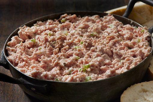 Canned meat fillet in a metal can on a wooden background. Selective focus.