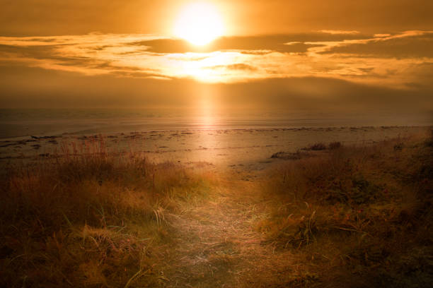 Barassie Shore Troon in Ayrshire Scotland with bright orange sunburst sky on a summer night, composite.