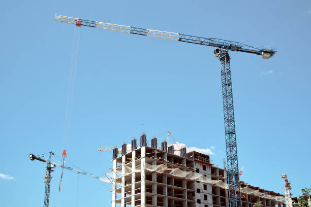 Construction site with frame of multistory buildings and cranes at blue sky