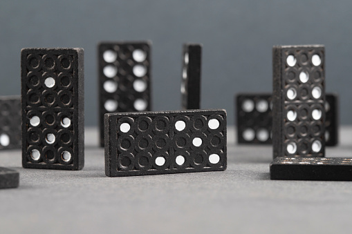 Black dominoes chain on a dark table background. Domino effect concept