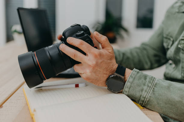 Photographer in home office working with laptop computer and looking at camera