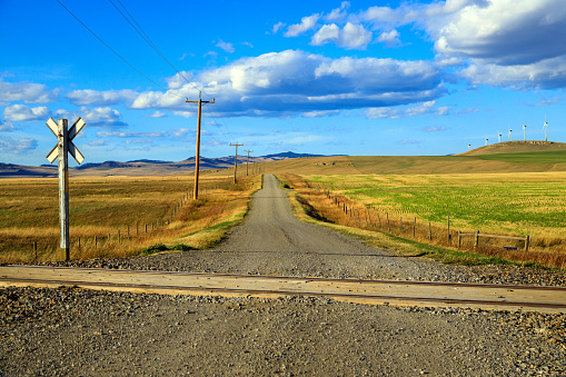 A Canadian prairie landscape with a dirt gravel country road near Pincher Creek, Alberta, Canada.