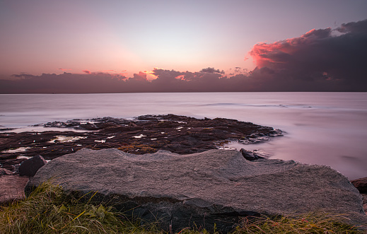 Seascape at Troon shore rocks at evening sunset with long exposure.