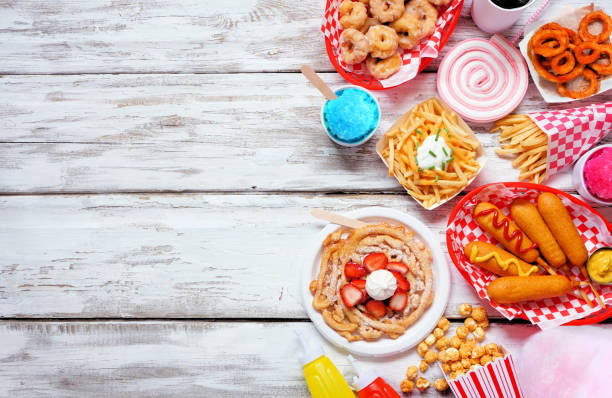 Carnival theme food side border over a white wood background Carnival theme food side border over a white wood background. Above view with copy space. Summer fair concept. Corn dogs, funnel cake, cotton candy and snacks. midway fair stock pictures, royalty-free photos & images