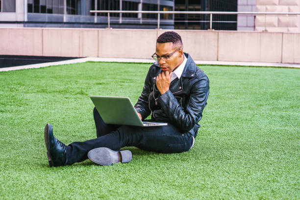 Young  black man working on laptop computer outdoors in New York City