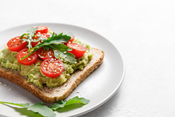 istock Avocado rye bread toast with cherry tomatoes and arugula on bright background. Healthy appetizer, breakfast, lunch or snack. Vegan food concept. Close up 1396361474