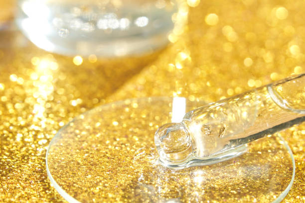 istock Serum gel texture swatch. Transparent drop with golden sparkles with bubbles 1396362238