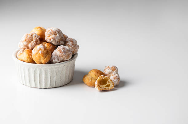 istock Bunuelos, Spanish small deep fried doughs in ceramic bowl on white background with napkin. 1396362310