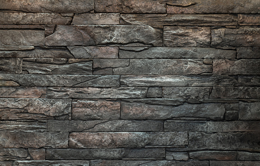 Soft light on pieces of Stone cladding wall. made of striped stacked slabs of natural brown rocks.
