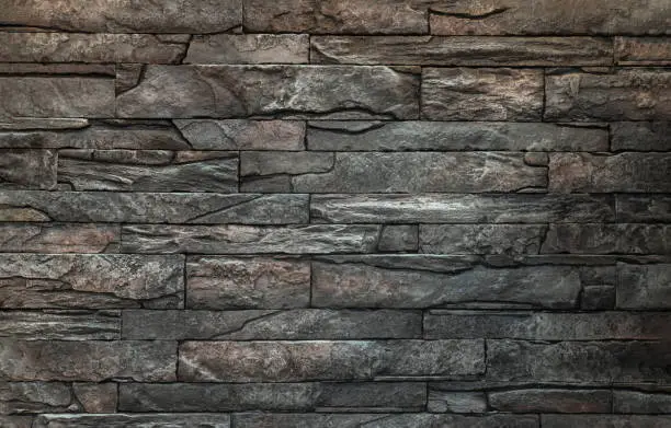 Photo of Soft light on pieces of Stone cladding wall. made of striped stacked slabs of natural brown rocks.