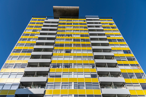 Council housing block, a faced with yellow panels in London, sunny day.