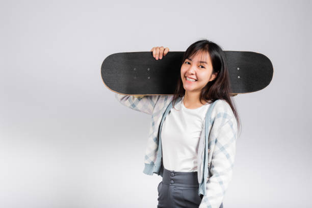 istock Smiling happy woman holding skateboard on shoulder 1396363740