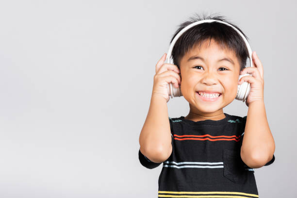 pequeño niño lindo de 5-6 años de edad escuchar música usar auriculares inalámbricos en estudio tomado aislado - 4 5 years fotografías e imágenes de stock