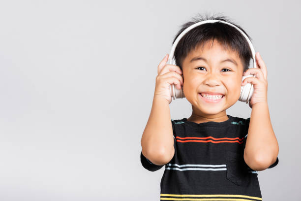 petit garçon mignon de 5 à 6 ans écouter de la musique porter des écouteurs sans fil en studio pris isolé - 4 5 years photos et images de collection