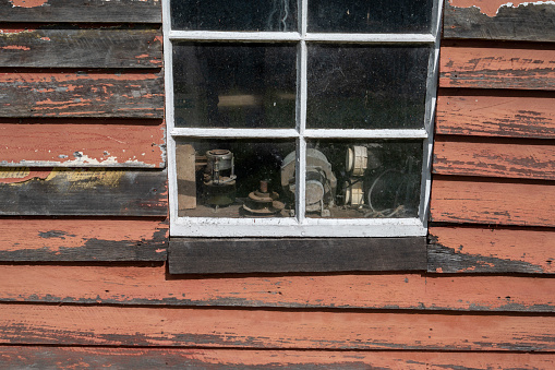 Old dark red wooden wall with window in white frame, typically Scandinavian living house architecture detail